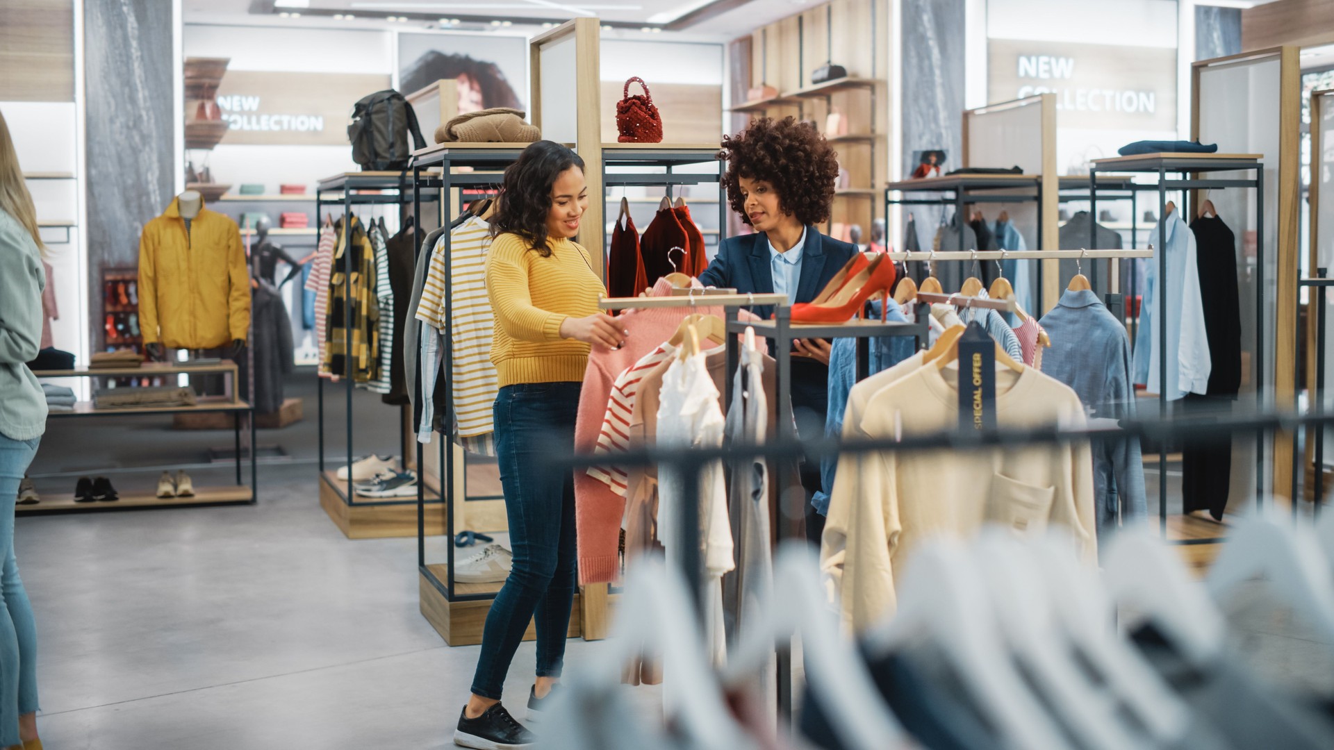 Customers Shopping in Modern Clothing Store, Retail Sales Associate Assists Client. Diverse People in Fashionable Shop, Choosing Stylish Clothes, Colorful Brand Designs, Quality Sustainable Materials.